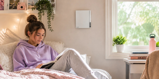 A teenager lying on her bed reading a book while a Vents-US-Twinfresh Expert provides fresh air for her room.